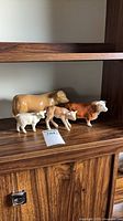 group of four ceramic cow figurines on wood shelf