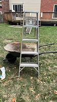 Full view of ladder and wheelbarrow together outdoors