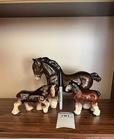 Group shot of three ceramic Clydesdale figurines with size reference