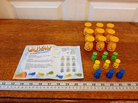 All components laid out with ruler: instruction sheet, large orange fish, blue, yellow, green small fish pieces