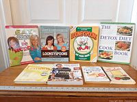 All eight books standing and laid out to show covers