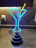 Lamp illuminated showing blue outline, yellow accent, green olive, on base