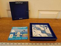 Open game showing tiles arranged on grid alongside challenge booklet and lid visible