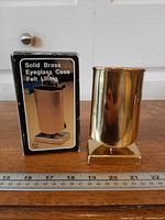 Eyeglass case beside original box with ruler for scale