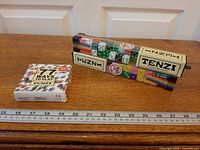 Tenzi dice game box and 77 Ways card deck next to ruler