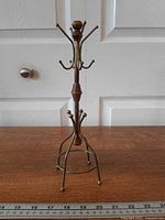 Full view of brass jewelry stand on wood surface