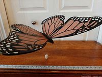 Full view of wooden monarch butterfly mobile on table showing wings and pull string
