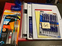 Group of packaged pens, pencils, notebooks, binder, sharpeners