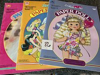 Front covers of three uncut paper doll books