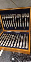 Open case showing 12 forks and 12 knives with mother-of-pearl handles