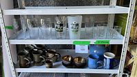 Entire lot on two shelving tiers showing all glassware, mugs, metal bowls, pitcher