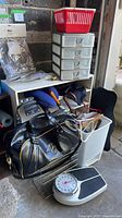 Overall lot showing scale, trash can, cube shelf, plastic drawers, red basket, duffel bag, wire rack