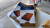 Two Napoleon bamboo cutting boards with packaging sleeves on table