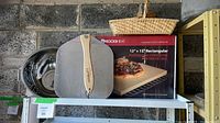 Group view of pizza stone box, peel, colander, basket on shelf
