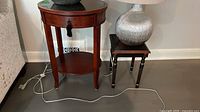 Round wood side table next to square accent table, lamps shown for scale