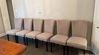 Front view of all six upholstered dining chairs aligned against wall