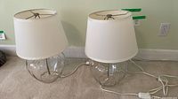 Both glass lamps with shades and cords visible