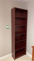 Full frontal view of tall dark cherry laminate bookcase showing five shelves