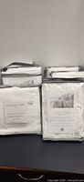 Packaged white bedding pieces, four packages visible