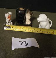 Group view of three ceramic dog items with tape measure for scale