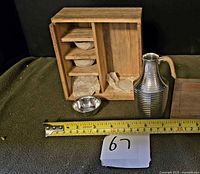 Overall view showing wooden box, metal flask, tape for scale, one cup visible