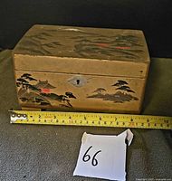 Front view of wood box with Japanese landscape, tape for scale