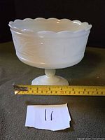 Side view of milk glass pedestal bowl with tape measure showing size