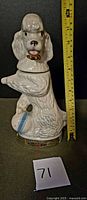 Front view of ceramic poodle decanter with ruler showing height