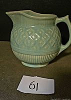 Left side view of aqua ceramic pitcher showing basketweave and ribbed design