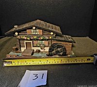 Front view of wooden Swiss chalet music box with measuring tape showing size