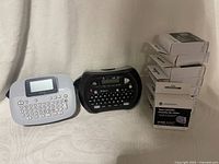 Two label makers with stack of tape cassette boxes