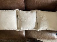 Three white down pillow inserts front view on sofa