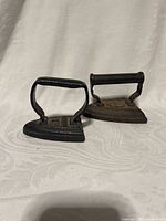 Pair of sad irons side by side showing handles and base shapes