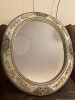 Full front view of oval mirror and decorative frame