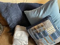 Group shot of pillows, folded sheet set and bedding textiles