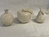 Three glazed ceramic fruit sculptures side by side