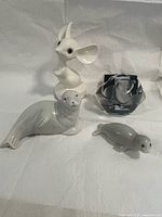 group shot of four figurines: crystal polar bear weight, white mouse, large grey seal, small grey seal