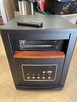 Front view of black LifeSmart heater with remote on top showing control panel and vent