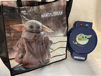 Front view of waffle maker next to Grogu tote bag