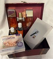 Overview of lot inside burgundy case showing perfumes, oils, foot pads and flashlight box