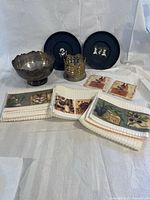 Group shot showing all items: silver bowl, bottle coaster, two black plates, tea towels, tile coasters