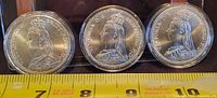 Three Queen Victoria commemorative tokens in capsules aligned side by side with ruler for scale