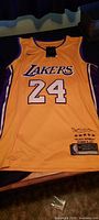 Front of gold Lakers #24 Kobe Bryant Nike jersey showing swoosh logo, Lakers lettering, number, and hem patch