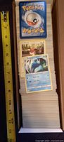 Open 660-count box filled to capacity with Pokémon cards, ruler for scale