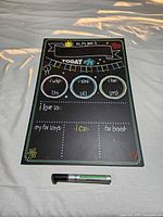 Front of black pre-printed baby milestone chalkboard with marker beneath