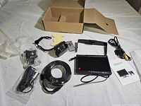 Complete kit laid out showing monitor, camera, cable, brackets, wiring harness, remote and box