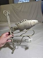 Full view of metal fish hanger bracket held by hand