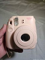 Front view of pastel pink Instax Mini 8 showing lens, flash, viewfinder, and branding