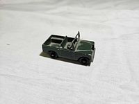 Side view of green diecast Land Rover truck on white background