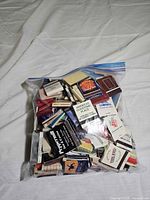 Front view of sealed freezer bag showing numerous vintage advertising matchbooks